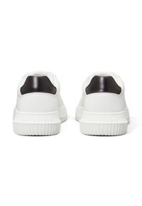 Sneakers bianchi con una finitura testurizzata, dotati di un tallone nero liscio e di una soletta in gomma rigata; il marchio è visibile sul lato.