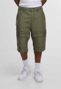 Olívazöld cargo rövidnadrág, több zsebbel, tartós anyagból, kontrasztos fehér varrással és térd fölötti hosszúsággal.