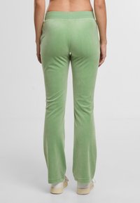 Zaļas samta platās bikses ar gludu tekstūru un plašu jostasvietu, kas piedāvā ikdienišķu piegriezumu un nedaudz brīvu siluetu.