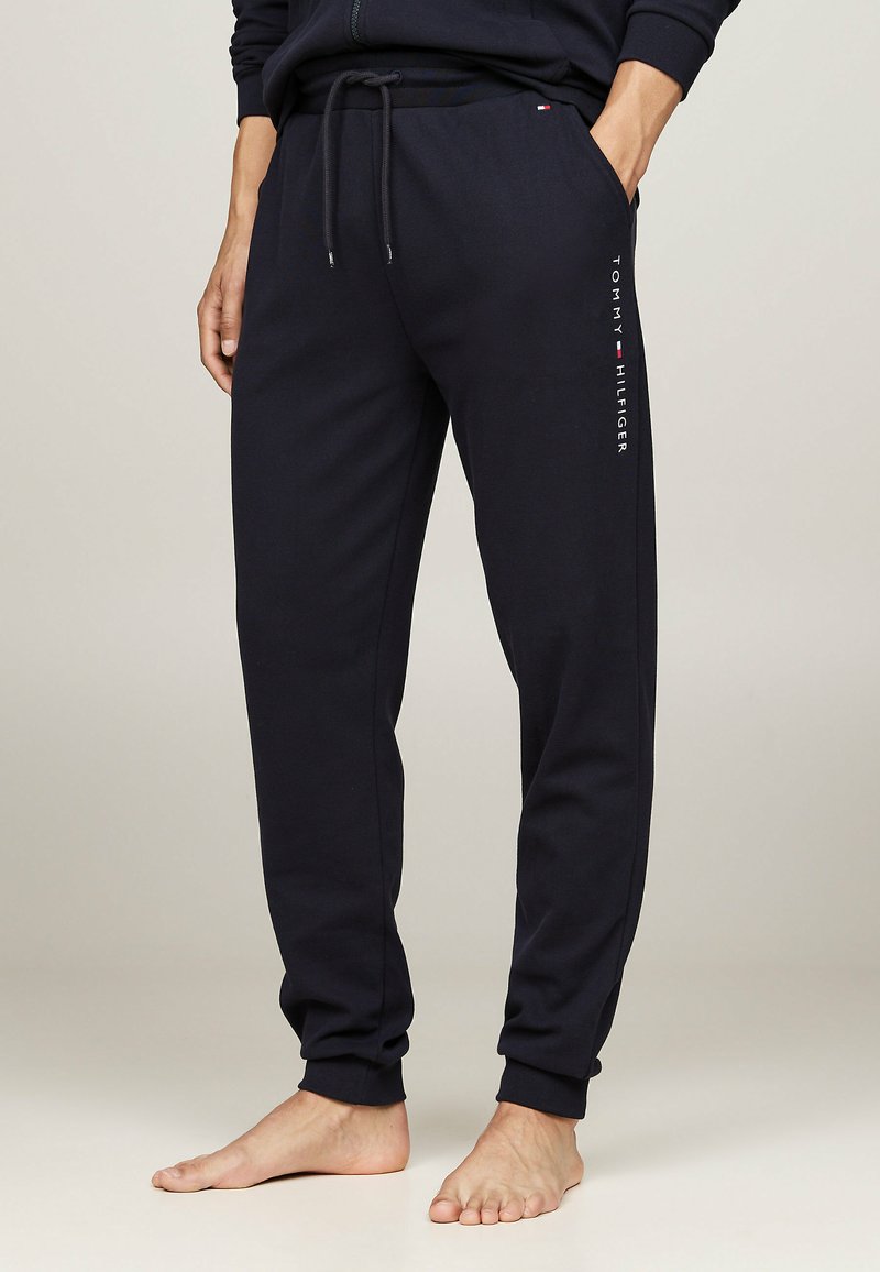 Marineblaue Sweatpants aus Baumwolle, mit elastischem Bund, seitlichen Taschen und dem "TOMMY HILFIGER"-Logo vertikal entlang des Beins.