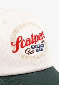 Gorra con un frente color crema que presenta el logotipo bordado "Scalper" en rojo y "ENERGY BAR" en azul, y una visera verde oscuro, de material de algodón.
