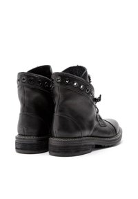 Botas de tobillo de cuero negro con punta redonda, cremallera lateral y acentos decorativos de remaches a lo largo del cuello. Suela de goma texturizada.