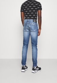 Tajta blå denimjeans med medelhög midja, femficksdesign och synlig Calvyn Klein-logotyp på den bakre midjebandet.