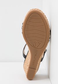 Černé espadrilky s tkaným juteovým klínem, gumovou podešví a velikostí 37 vyraženou na spodní straně. Texturovaná podrážka zajišťuje přilnavost.