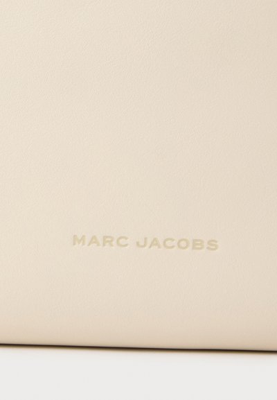 Surface en cuir lisse couleur crème avec texte en relief "MARC JACOBS" centré près du bas.