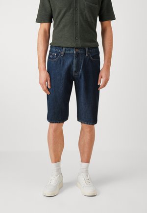 Dark blue denim shorts with a straight cut, featuring five pockets, belt loops, and a slightly distressed hem. Paired with a dark green shirt.