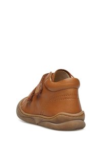 Scarpa in pelle marrone con punta arrotondata, texture morbida e una fascia in velcro. Suola in gomma flessibile con un leggero motivo a rilievo.
