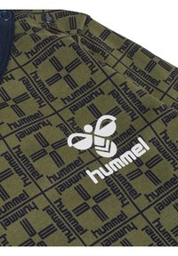 Groene stof met herhaaldelijk zwart "hummel" tekst en logo; heeft een wit logo en een gestructureerd ontwerp; knoopsluiting bij de hals.