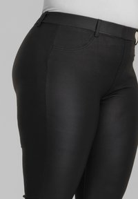 Mustat, korkea vyötäröiset legginssit, joissa on sileä ja kiiltävä pinta. Ominaisuuksiin kuuluu etutasku, huomaamaton ommel ja tiukka malli.