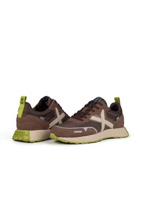 Chaussures de sport marron en matériaux en maille et en daim. Comprennent des accents vert lime, des rayures beiges sur les côtés et une semelle en caoutchouc texturé.