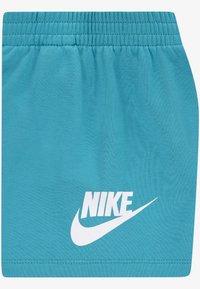 Světle modré šortky Nike s elastickým pasem a bílým logem na přední dolní části. Vyrobené z texturované látky, navržené pro pohodlí.