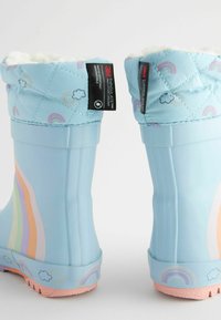 Botas de lluvia de goma azules con parte superior de textil acolchado, que presentan un patrón de arcoíris en tonos pastel y una suela texturizada de color rosa. Aislamiento interior para mantener el calor.