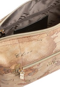 Pochette da viaggio beige con stampa di una mappa del mondo vintage, cerniera dorata e un portafoglio nero parzialmente visibile all'interno del compartimento principale.