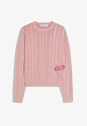 Pull en maille torsadée rose avec manches longues, poignets et ourlet côtelés, et un petit patch brodé sur le côté inférieur gauche.