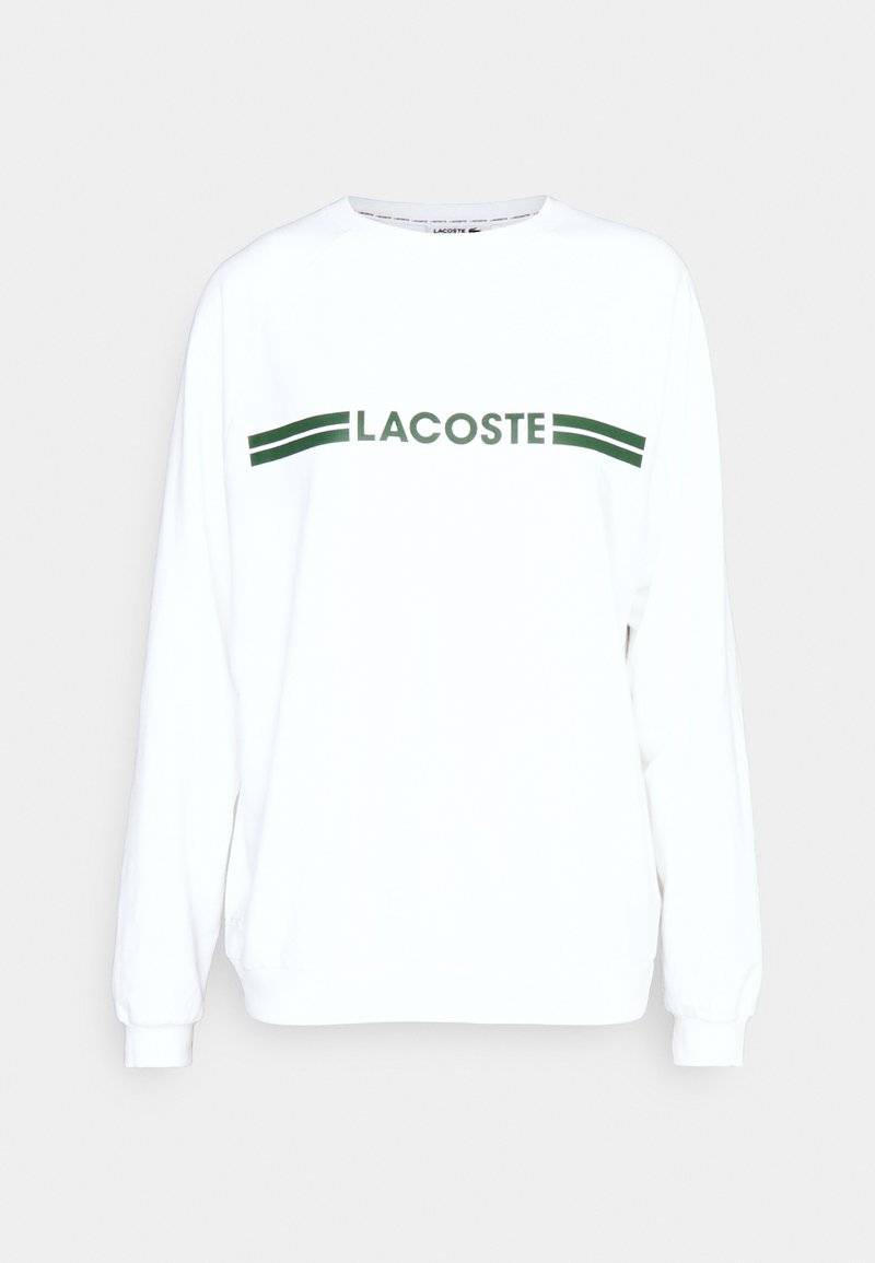Sweatshirt long à manches blanches avec le texte "LACOSTE" vert et des rayures sur la poitrine. Fabriqué en tissu doux et léger. Coupe décontractée.