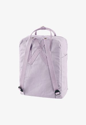 Mochila de tela lila con forma cuadrada, que cuenta con correas de punto cruz y dos asas en la parte superior, textura suave y diseño minimalista.