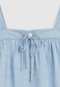Light blue top featuring a gathered design, thin straps, and a tied detail at the back with a circular cutout. Soft, textured fabric.