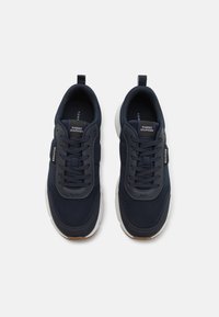 Een paar marineblauwe Tommy Hilfiger sneakers met witte zolen, mesh stof en merklabels op de tong en de zijkant, getoond vanuit een bovenaanzicht.