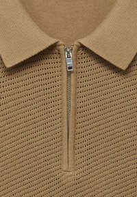Beige gebreid poloshirt met een textuurdesign, halve ritssluiting met metalen hardware en een klassieke kraag.