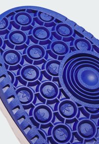 Blue rubber shoe sole featuring circular patterns, textured accents, and concentric rings. Notable embossed logo designs throughout.