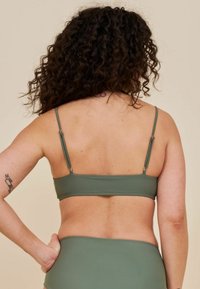 Top bikini verde oliva con spalline sottili regolabili, forma rettangolare, design minimalista, texture liscia e dettagli in metallo argentato.