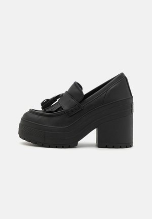 Sort chunky platform loafer med blokhæl, kvast og frynse detaljer, struktureret sål og slip-on design.