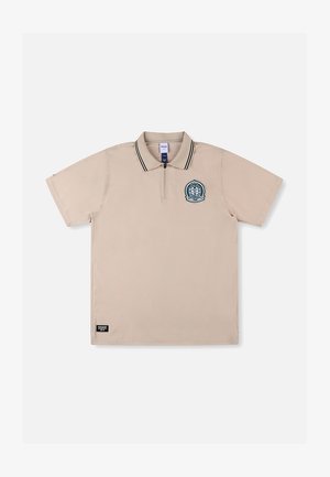 Polo beige à manches courtes avec un col zippé, des accents rayés noirs et blancs, et un logo circulaire brodé sur le côté gauche de la poitrine.
