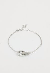 Pulsera de cadena de plata con un broche de eslabón ovalado y un acento circular texturizado, adornada con pequeñas piedras transparentes.