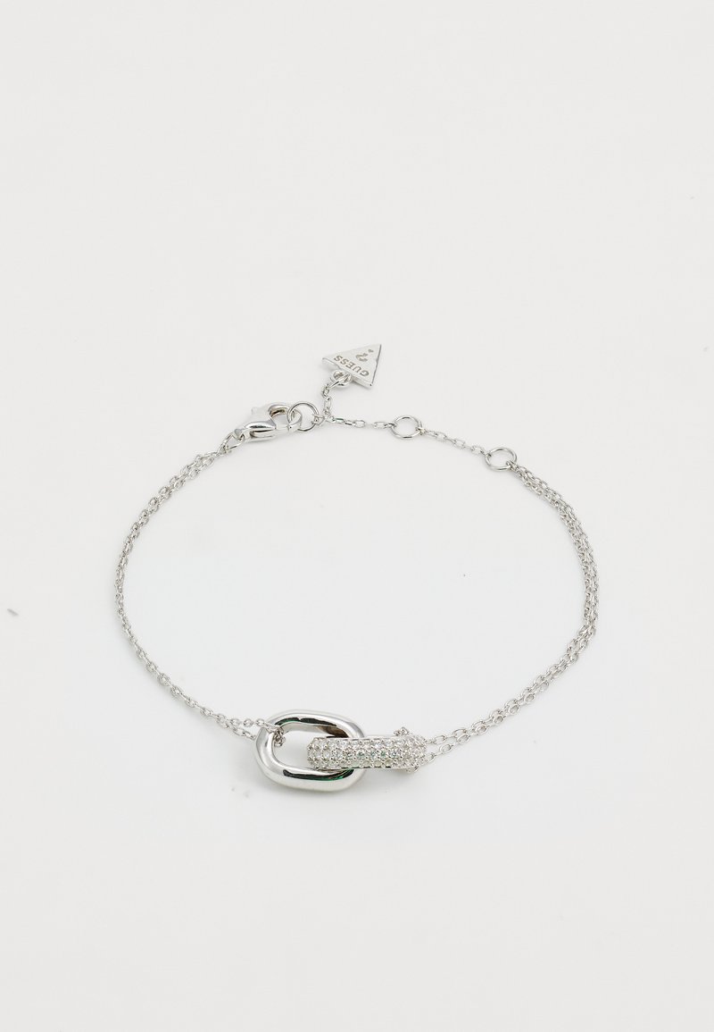 Pulsera de cadena de plata con un broche de eslabón ovalado y un acento circular texturizado, adornada con pequeñas piedras transparentes.