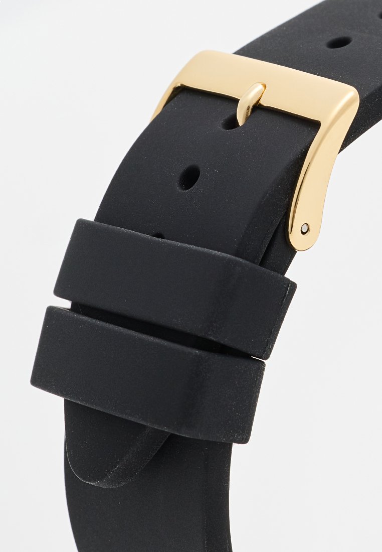 Correa de reloj de silicona negra con hebilla de metal dorado. La correa tiene una textura suave y un ajuste ajustable con múltiples orificios.