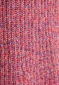 Tissu tricoté en rouge, rose et bleu avec un motif texturé de mailles entrelacées, présentant une finition en fil multicolore doux.