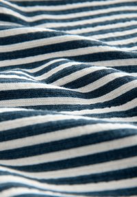 Blåt og hvidt stribet stof med en blød tekstur, der har jævnt fordelte horisontale striber, som skaber et bølgelignende mønster.