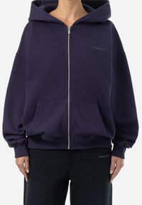 Felpa con zip color blu navy realizzata in morbido cotone, dotata di un ampio cappuccio, tasche frontali e polsini e orlo a costine. Logo sul petto.