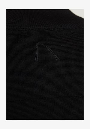 Fekete kötött anyag ribbes szerkezettel, kis, halvány varrási részlet a nyak területén.