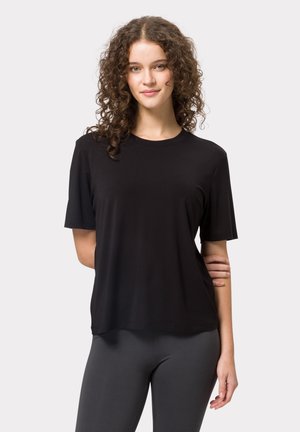 Sort kortærmet t-shirt lavet af glat stof med rund halsudskæring og afslappet pasform, parret med mørke leggings.
