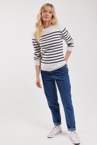 Gestreepte gebreide sweater in wit en marineblauw, relaxed fit, gecombineerd met lichtgewassen denim jeans, opgerolde mouwen en witte sneakers.