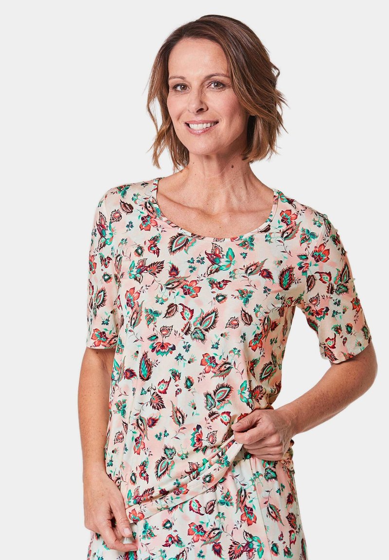 Floral short-sleeve blouse in light peach with green and red flower patterns, round neckline, and soft fabric texture.