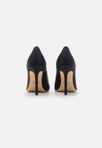 Scarpe decollété nere in satin con punte affusolate e tacchi sottili. Presentano una texture morbida e un logo discreto sulla suola.