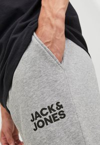 Gray sweatpants with a soft texture, featuring a black logo print of "JACK & JONES" on the lower left side and side pockets.