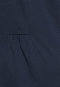 Tecido de algodão azul marinho com uma textura suave, apresentando detalhes franzidos ao longo da costura para um ajuste descontraído.