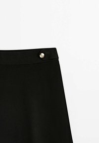 Jupe noire à texture lisse, avec un bouton argenté à la ceinture. Design simple, coupe droite. Pas de motifs ni d'accents supplémentaires.