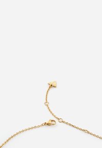 Gouden ketting met een driehoekige hanger en een karabijnsluiting. De ketting heeft een delicate schakeling en een glanzende afwerking.