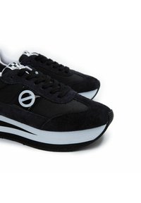 Zwarte suède en mesh sneakers met een opmerkelijk gelaagd ontwerp, voorzien van een witte streep op de zool en een ronde logo-accent.