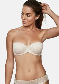 Soutien-gorge sans bretelles couleur crème avec une superposition en dentelle, des bords festonnés et un petit nœud au centre. Tissu doux avec un motif floral.