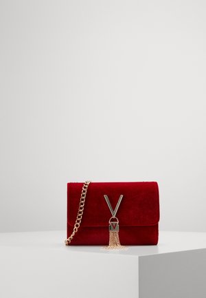 Borsa a mano in velluto rosso con tracolla in catena dorata, dotata di una chiusura metallica a forma di V e un dettaglio con nappina sul fronte. Design rettangolare.