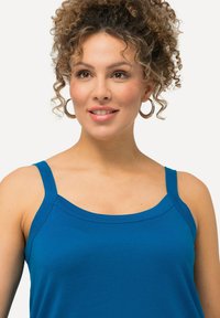 Top in cotone blu con spalline larghe, scollatura rotonda e texture liscia; presenta un design aderente.