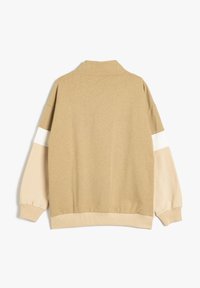 Sweatshirt beige avec un col, manches longues ornées d'accents blancs et beige clair, tissu texturé, et bords côtelés au niveau des poignets et de l'ourlet.