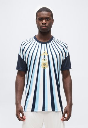 Mand stående vendt fremad iført en blå, hvid og sort stribet fodboldtrøje med Argentina Football Association-logo og Adidas-logo.