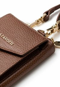 Borsa a tracolla in pelle marrone con una finitura testurizzata, dotata di hardware dorato, chiusura a pattina e tracolla staccabile. Dettaglio del logo dorato visibile.