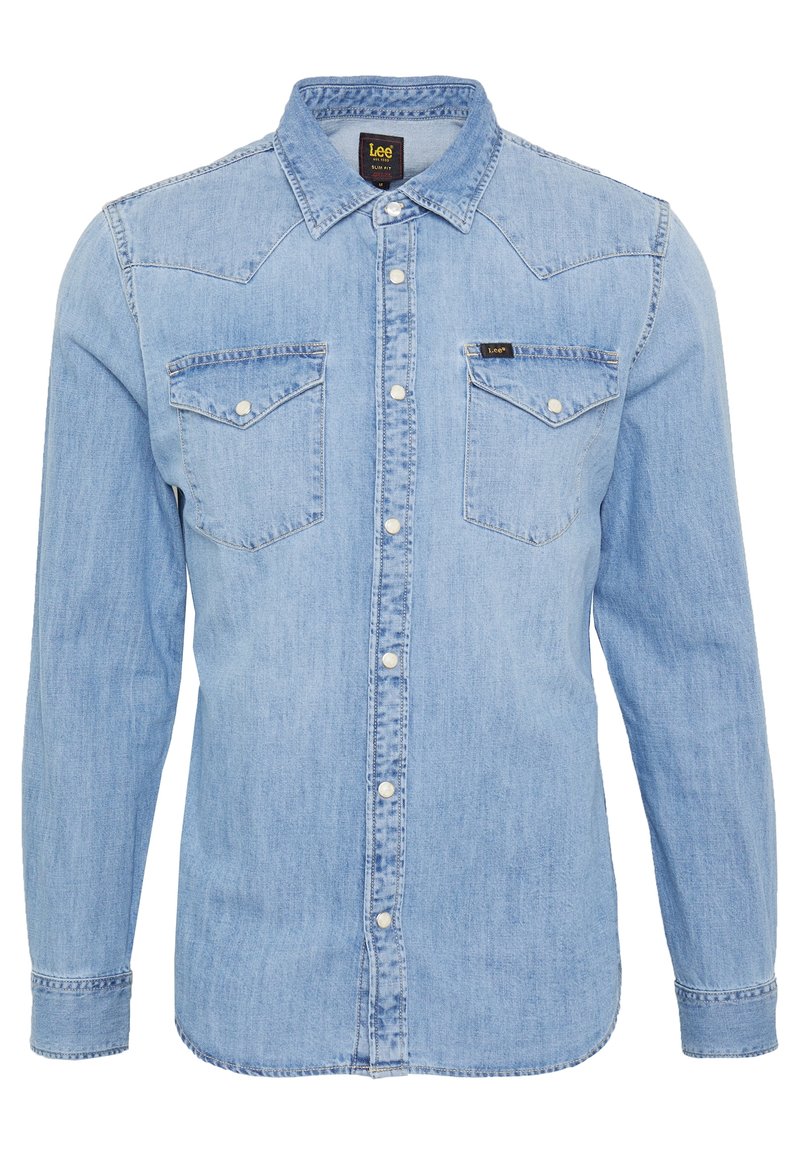 Chemise en jean bleu clair à manches longues avec fermeture par boutons, deux poches poitrine à rabat avec boutons, et col pointu, étiquetée « Lee » sur la poche et le col.
